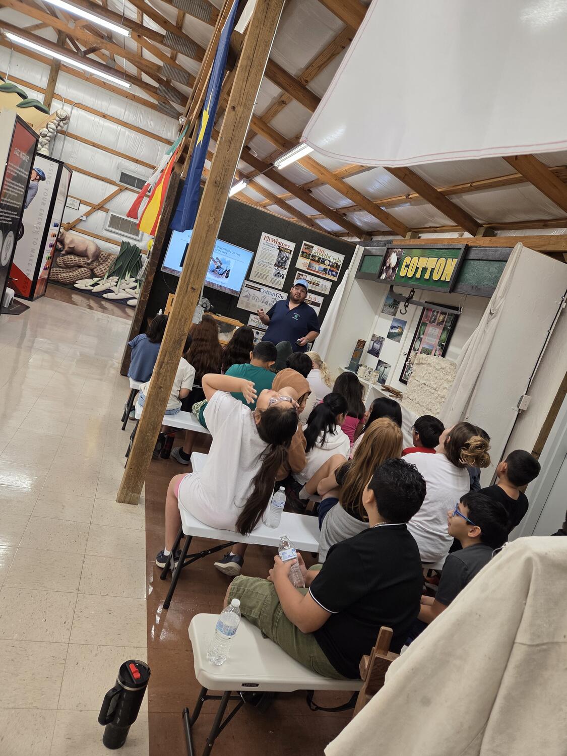 Students on benches listening to a lesson at the cotton exhibit in the Ag Education Wing