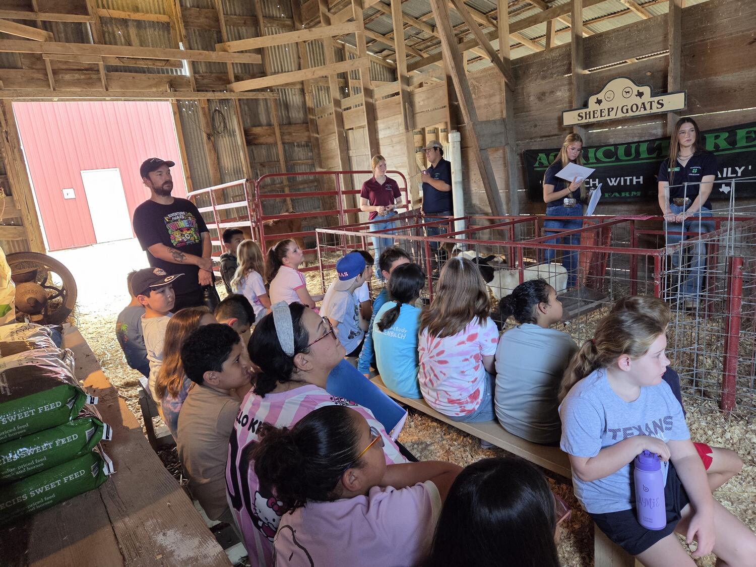 Students seated in the sheep and goat barn while young presenters lead the lesson